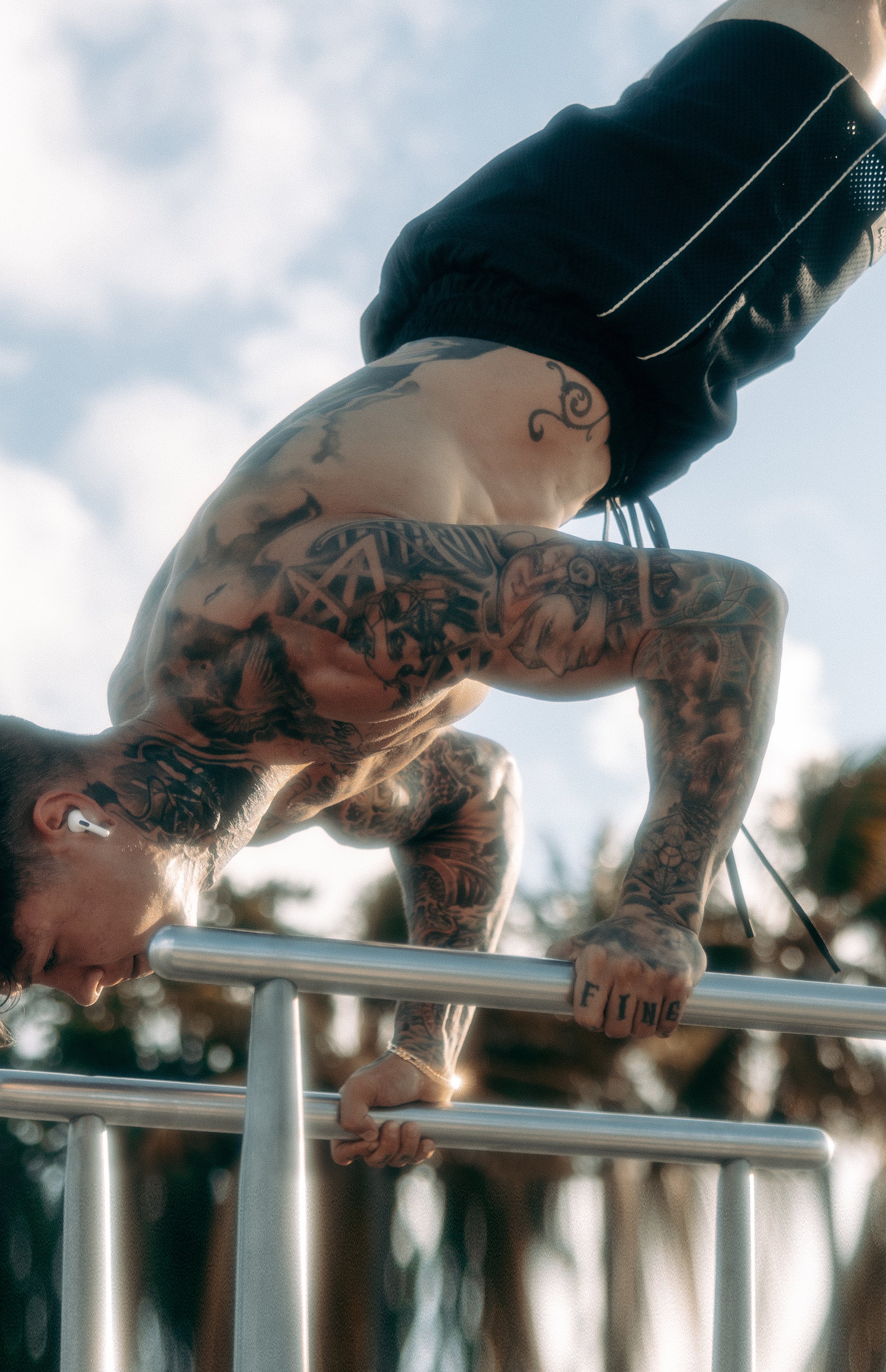 Chris Heria doing a handstand over metal bars, while wearing the black Heria mesh shorts. 